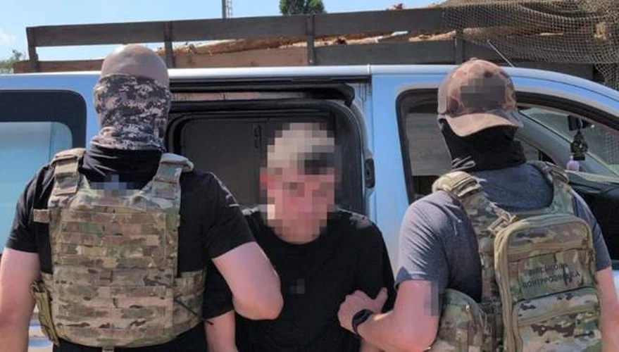 Співробітники СБУ під час затримання російського агента та вилучені речові докази